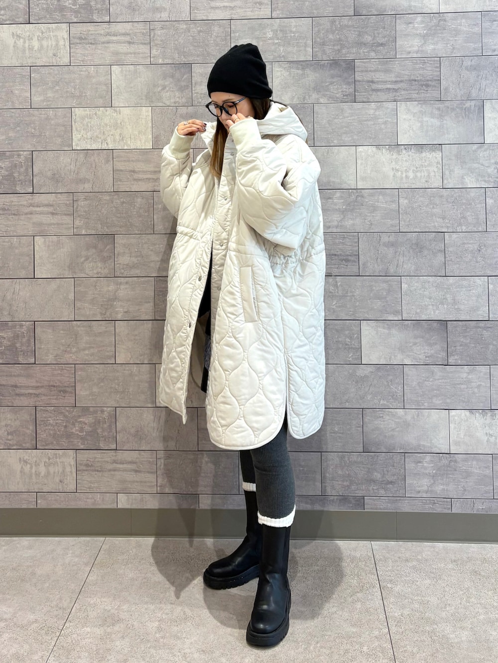 ホワイト系のダウンジャケット/コート、ブラック系のショルダーバッグ、ブラック系のブーツを着用したレディースの秋コーディネートの2枚目の写真