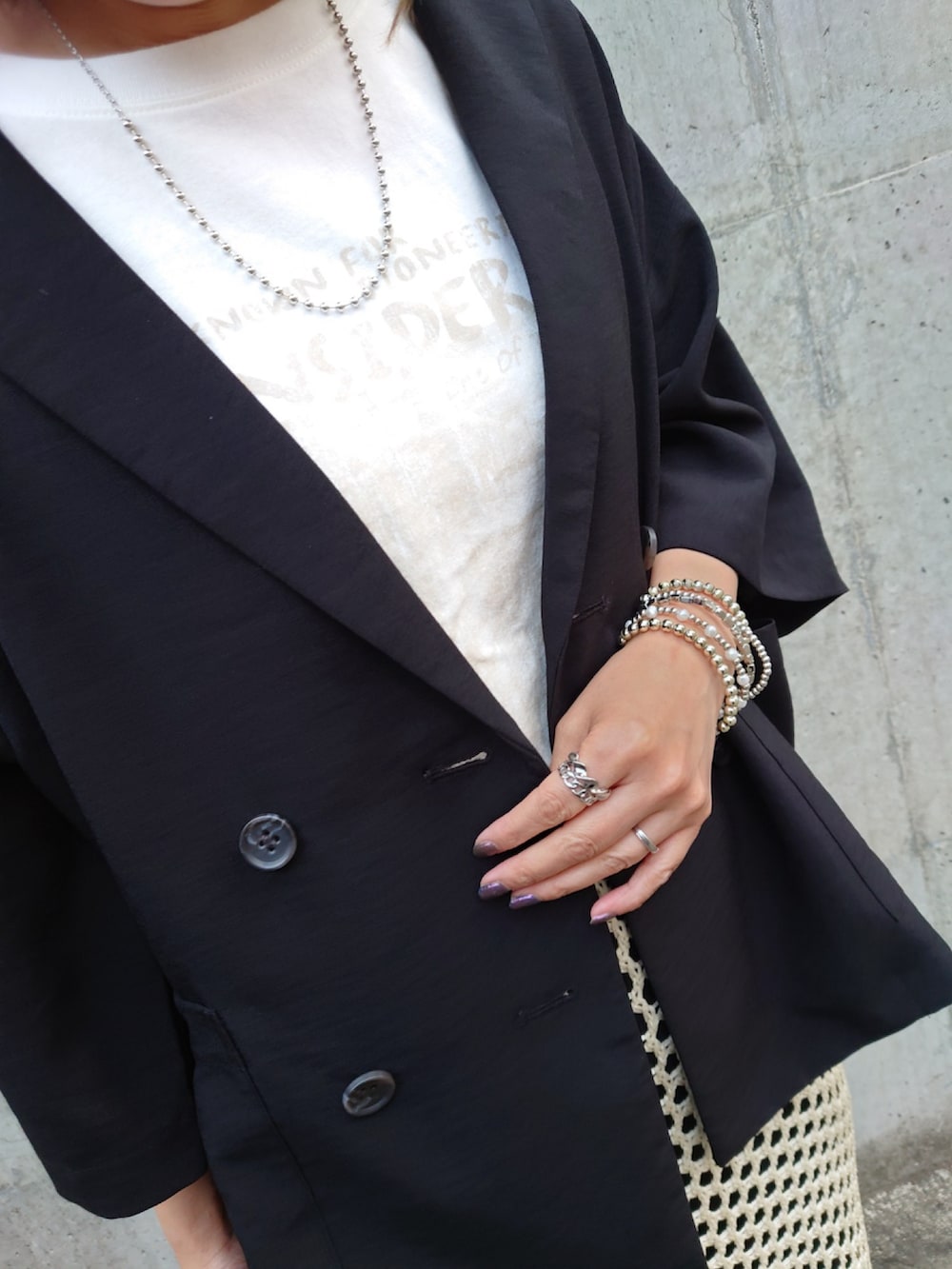 ブラック系のテーラードジャケット、ホワイト系のTシャツ/カットソー、ホワイト系のスカートを着用したレディースの夏コーディネートの3枚目の写真