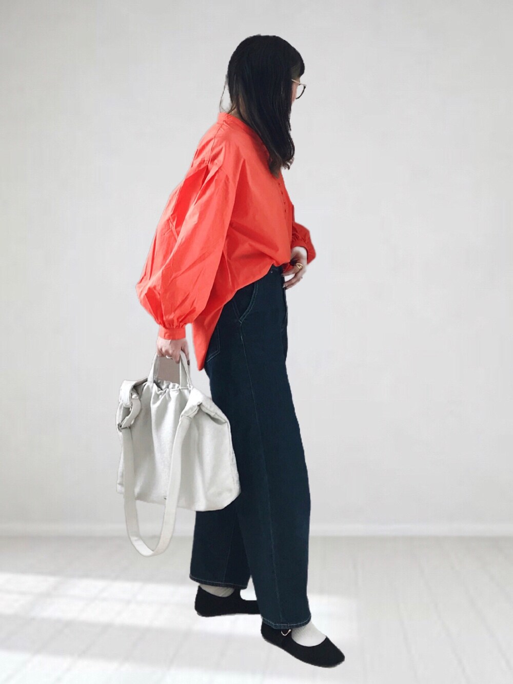 オレンジ系のシャツ/ブラウス、ブルー系のデニムパンツ、ホワイト系のトートバッグを着用したレディースの春コーディネートの2枚目の写真