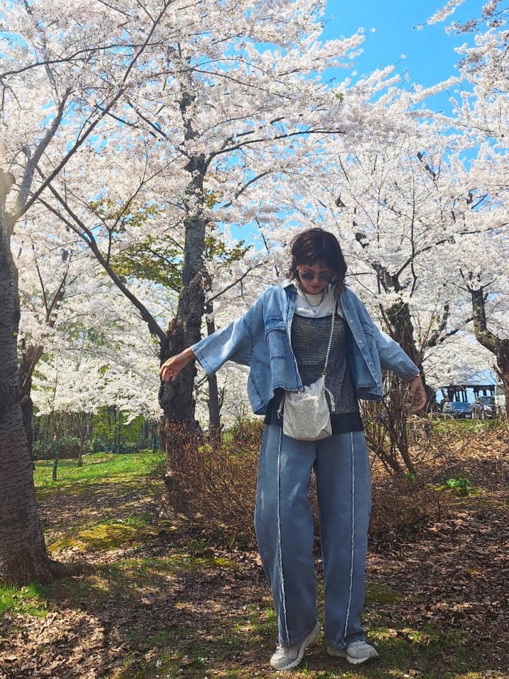 ブルー系のシャツ/ブラウス、ブルー系のデニムパンツ、ブラック系のワンピースを着用したレディースの春コーディネートの3枚目の写真