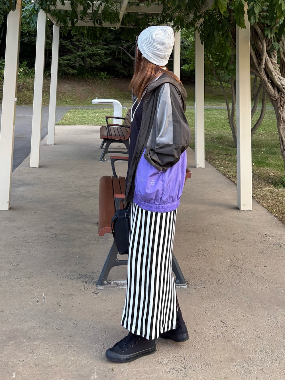 ブラック系のマウンテンパーカー、ホワイト系のスカート、ブラック系のスニーカーを着用したレディースの秋コーディネートの2枚目の写真