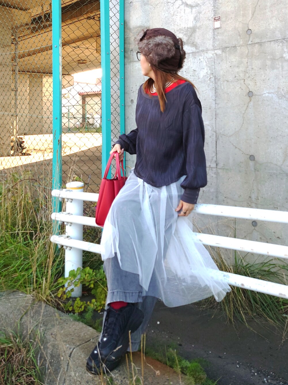 グレー系のデニムパンツ、ブラック系のスニーカー、ホワイト系のスカートを着用したレディースの秋コーディネートの3枚目の写真