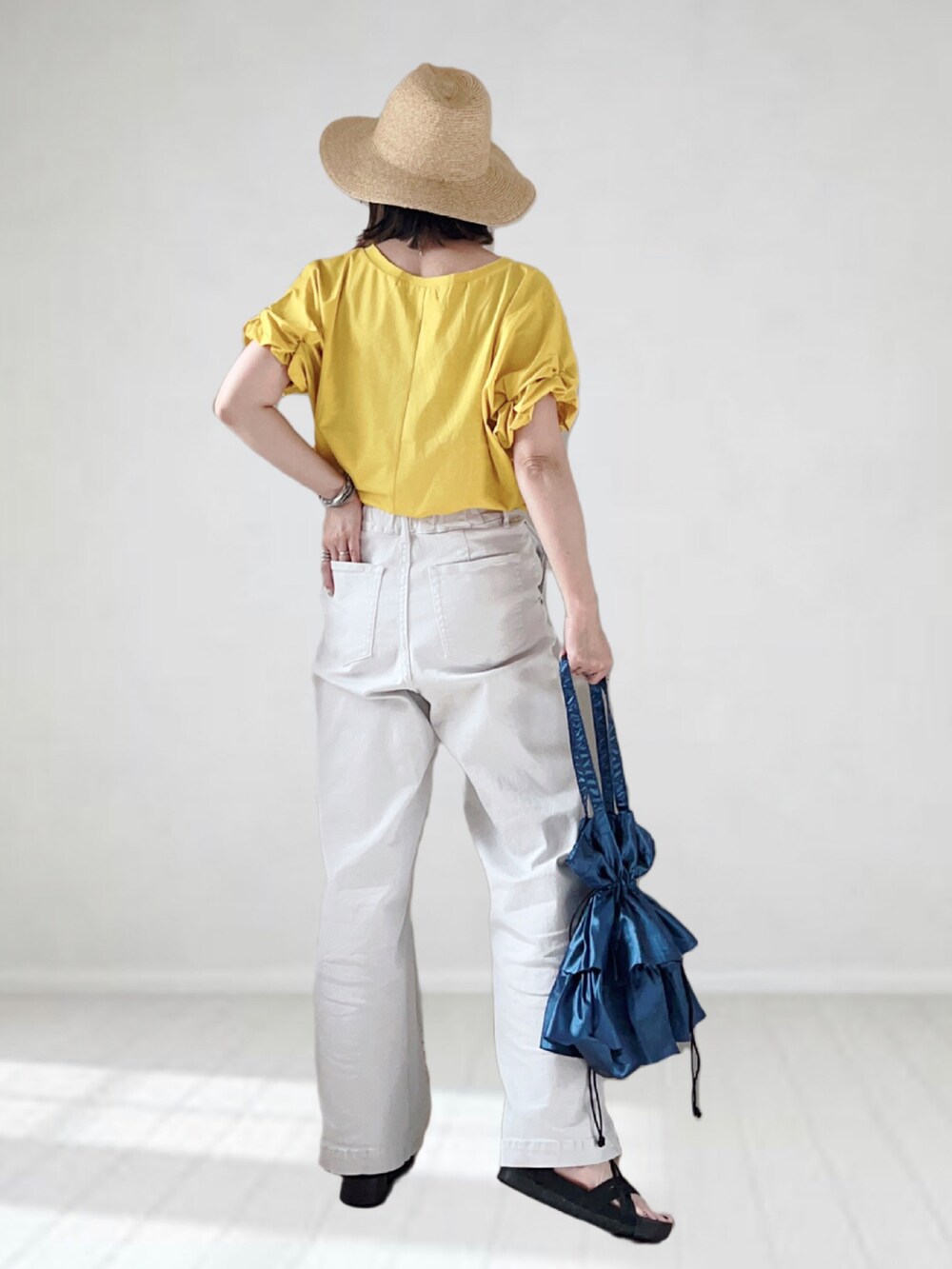 イエロー系のTシャツ/カットソー、グレー系のパンツ、ブルー系のバッグを着用したレディースの夏コーディネートの2枚目の写真