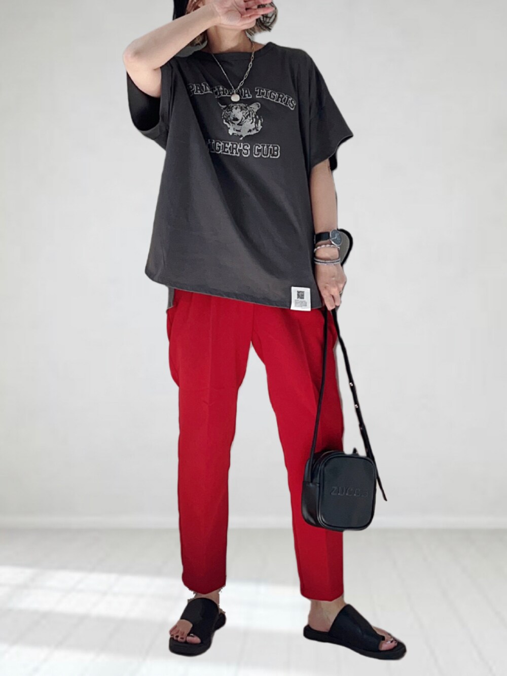 グレー系のTシャツ/カットソー、レッド系のスラックス、ブラック系のショルダーバッグを着用したレディースの夏コーディネートの4枚目の写真
