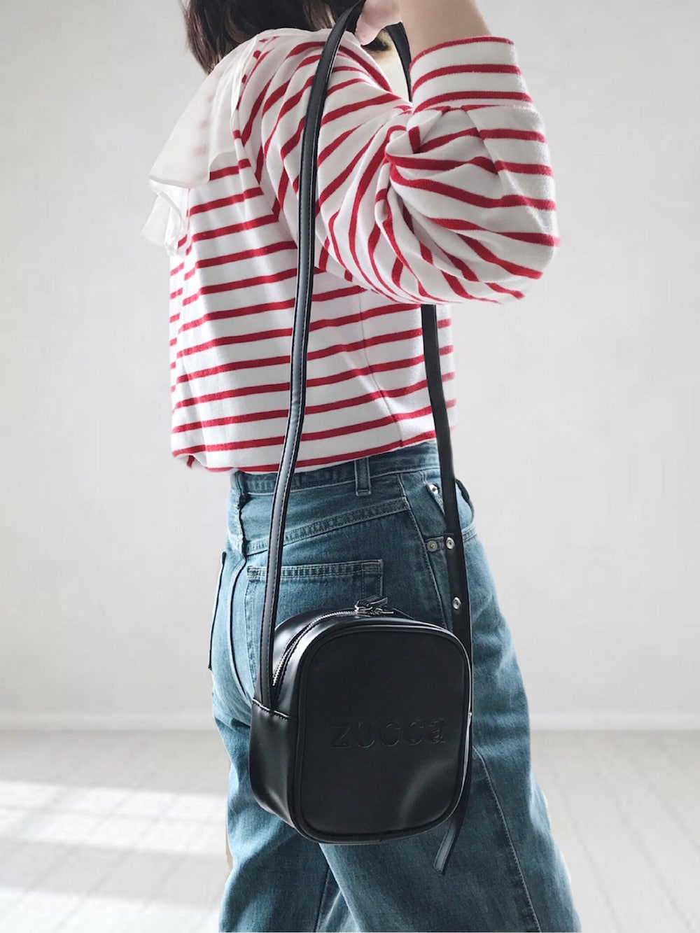 ブルー系のデニムパンツ、ホワイト系のTシャツ/カットソー、ブラック系のショルダーバッグを着用したレディースの春コーディネートの2枚目の写真