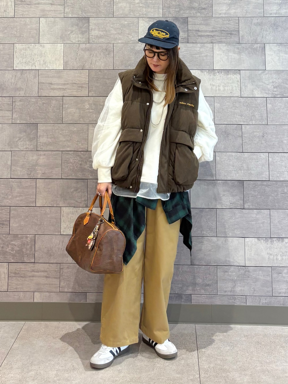 ブラウン系のダウンベスト、ホワイト系のスウェット、グリーン系のシャツ/ブラウスを着用したレディースの冬コーディネートの2枚目の写真