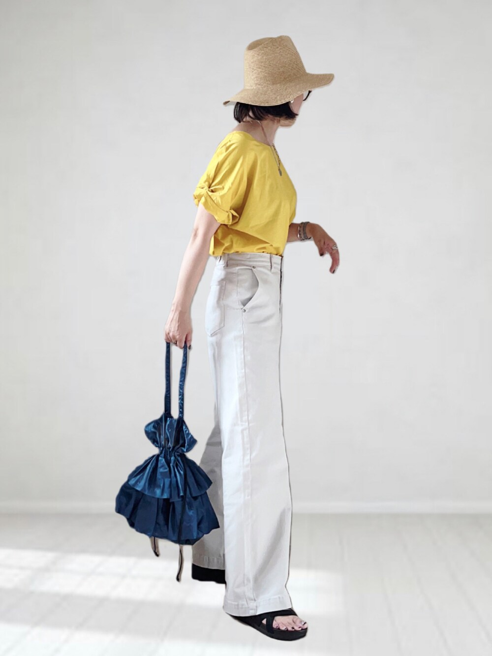 イエロー系のTシャツ/カットソー、グレー系のパンツ、ブルー系のバッグを着用したレディースの夏コーディネートの3枚目の写真