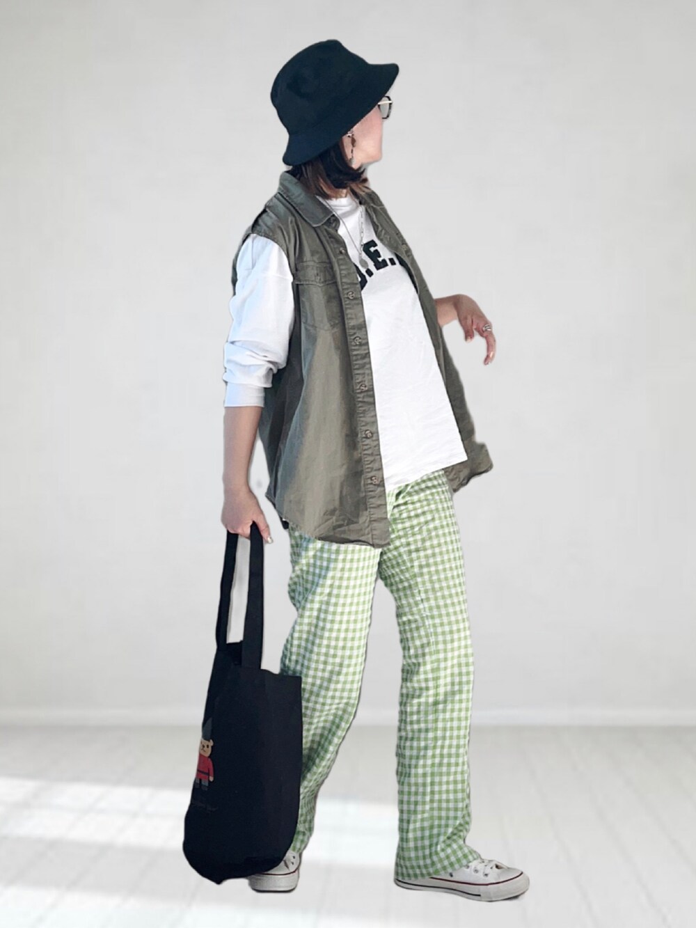 ホワイト系のTシャツ/カットソー、グリーン系のベスト、グリーン系のパンツを着用したレディースの春コーディネートの2枚目の写真