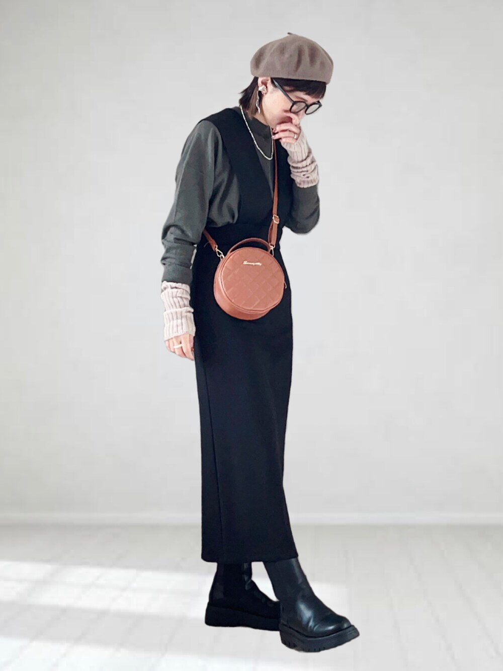 ブラック系のジャンパースカート、ブラック系のニット/セーター、ブラウン系のショルダーバッグを着用したレディースの秋コーディネートの3枚目の写真