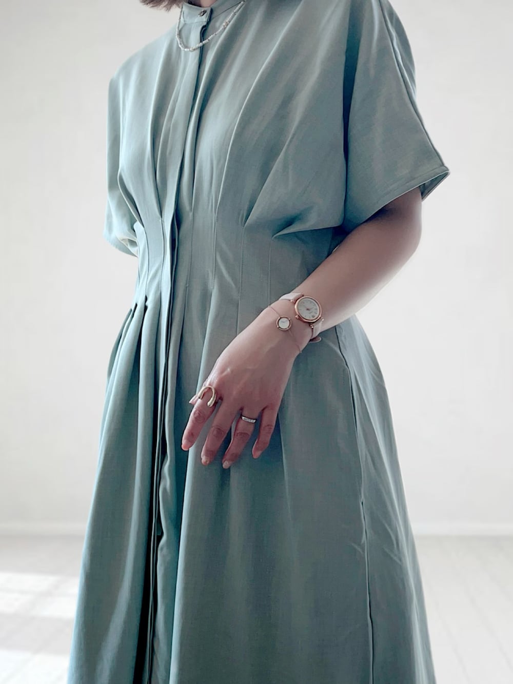 グリーン系のワンピース、ブラック系のかごバッグ、ホワイト系のサンダルを着用したレディースの春コーディネートの3枚目の写真