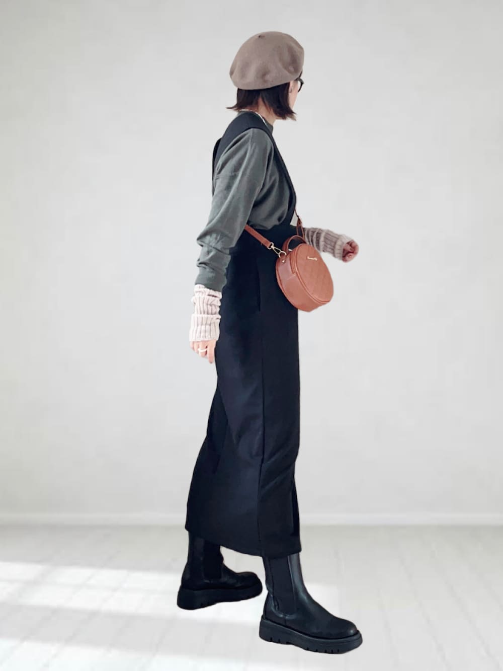 ブラック系のジャンパースカート、ブラック系のニット/セーター、ブラウン系のショルダーバッグを着用したレディースの秋コーディネートの4枚目の写真