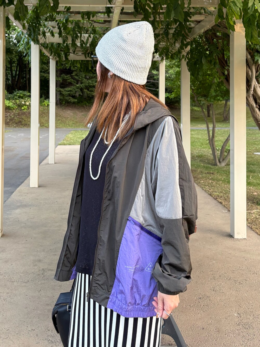 ブラック系のマウンテンパーカー、ホワイト系のスカート、ブラック系のスニーカーを着用したレディースの秋コーディネートの5枚目の写真