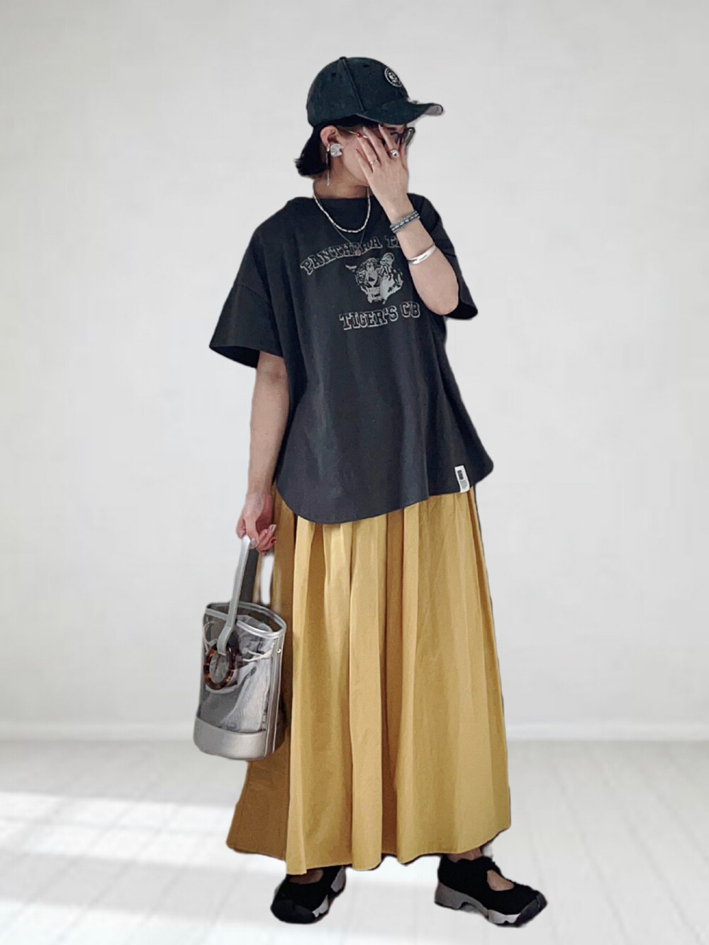 グレー系のTシャツ/カットソー、イエロー系のスカート、シルバー系のショルダーバッグを着用したレディースの夏コーディネートの2枚目の写真