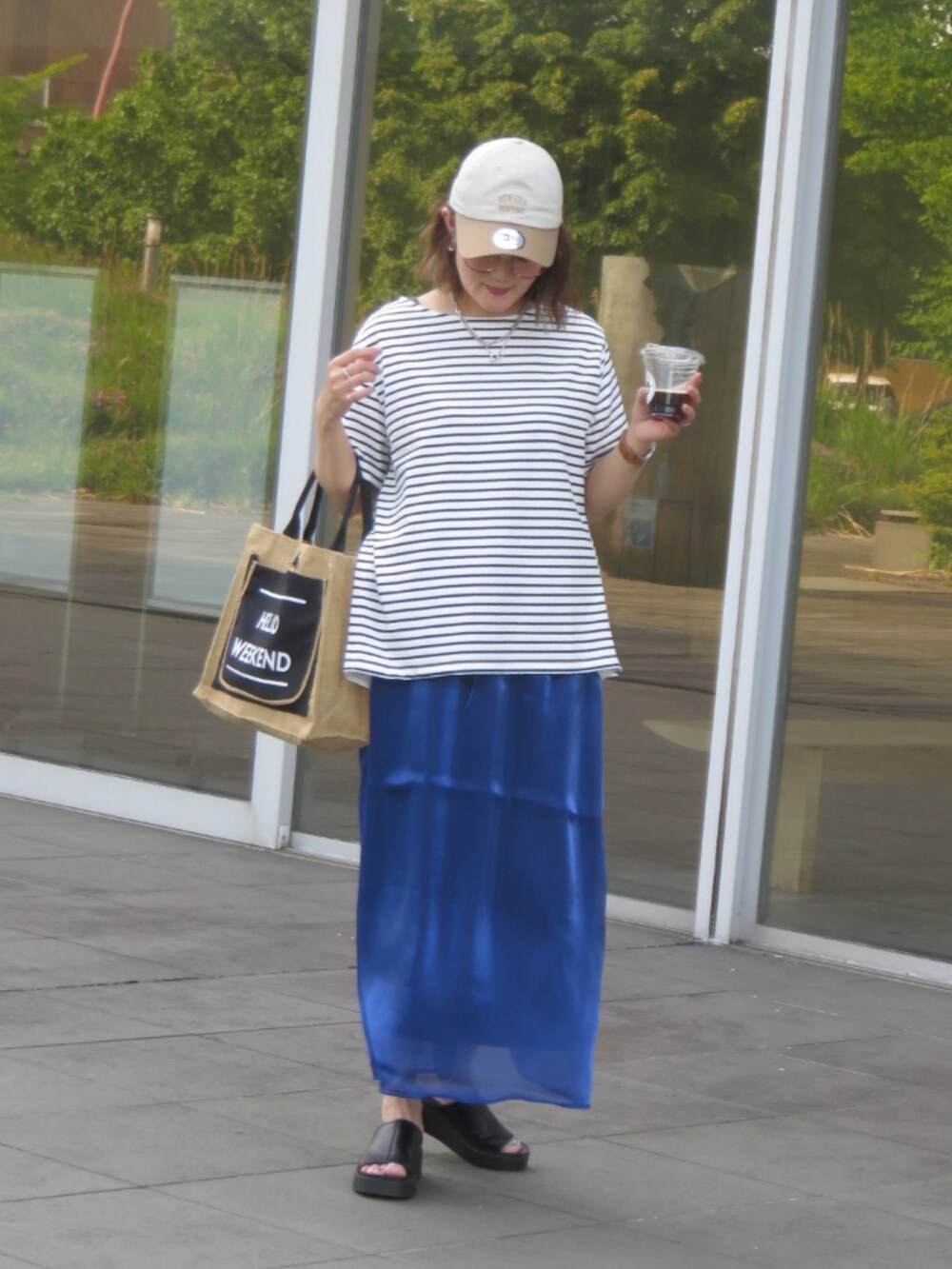 ホワイト系のTシャツ/カットソー、ブルー系のスカート、ブラック系のサンダルを着用したレディースの夏コーディネートの3枚目の写真