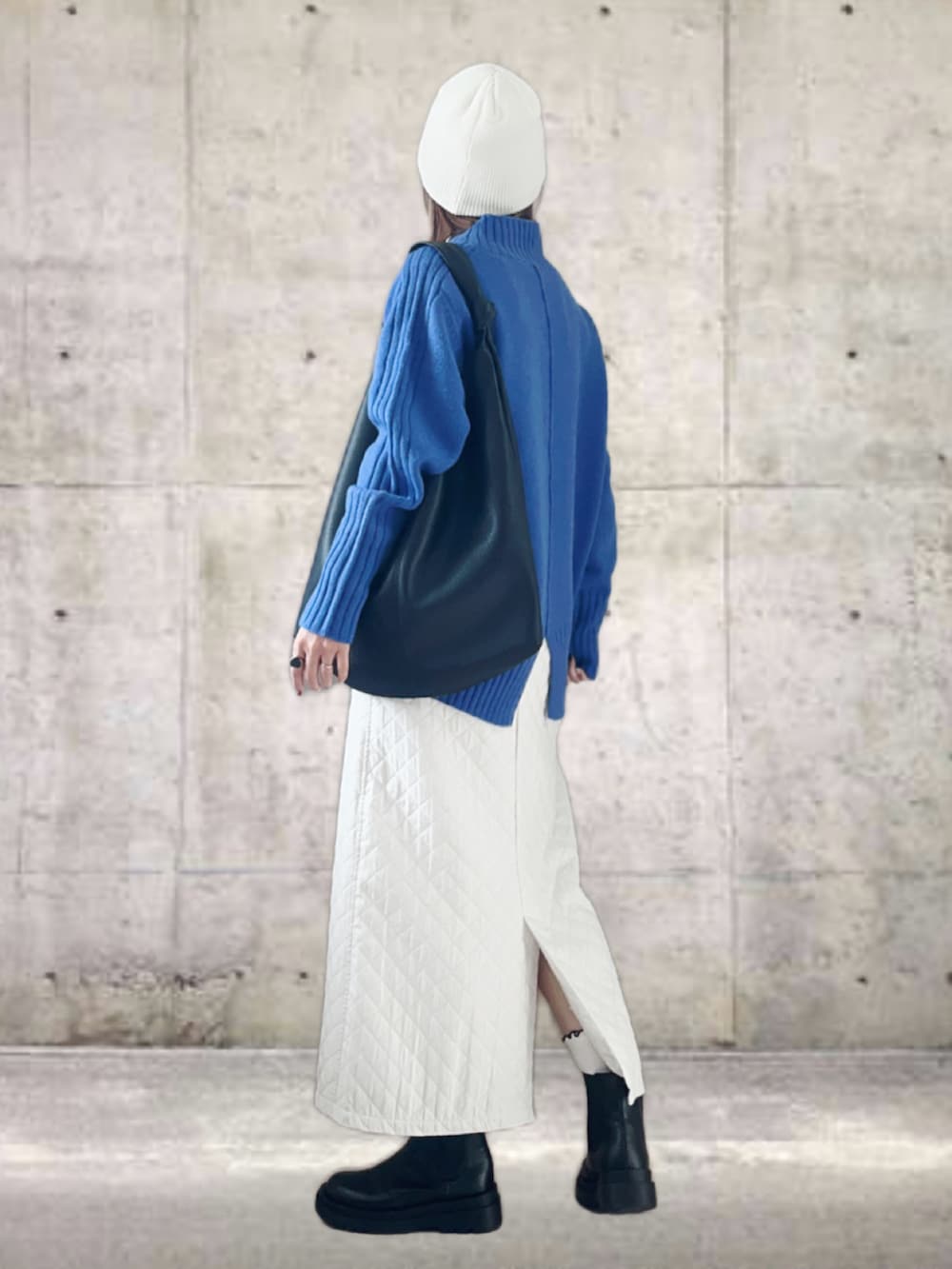 ブルー系のニット/セーター、ホワイト系のスカート、ブラック系のトートバッグを着用したレディースの冬コーディネートの2枚目の写真