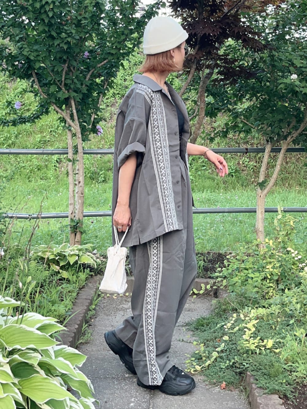 グレー系のシャツ/ブラウス、グレー系のその他パンツ、ブラック系のスニーカーを着用したレディースの夏コーディネートの4枚目の写真