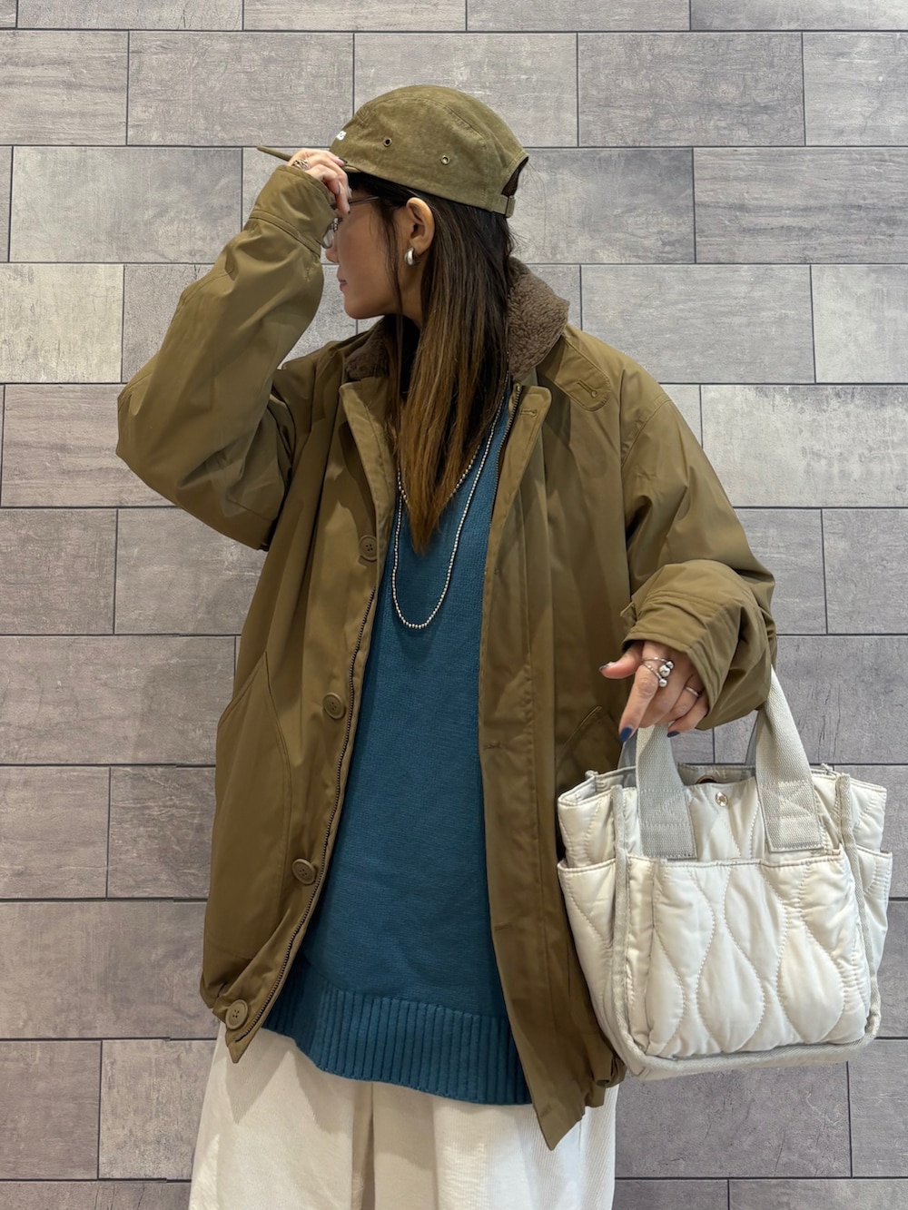 ベージュ系のミリタリージャケット、ブルー系のニット/セーター、ホワイト系のその他パンツを着用したレディースの冬コーディネートの2枚目の写真