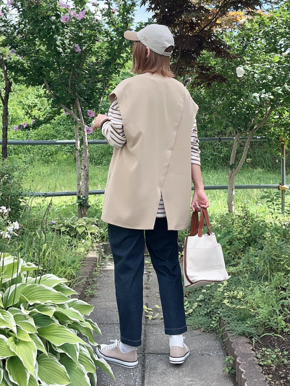 ブルー系のその他パンツ、ベージュ系のスニーカー、ベージュ系のベストを着用したレディースの秋コーディネートの3枚目の写真