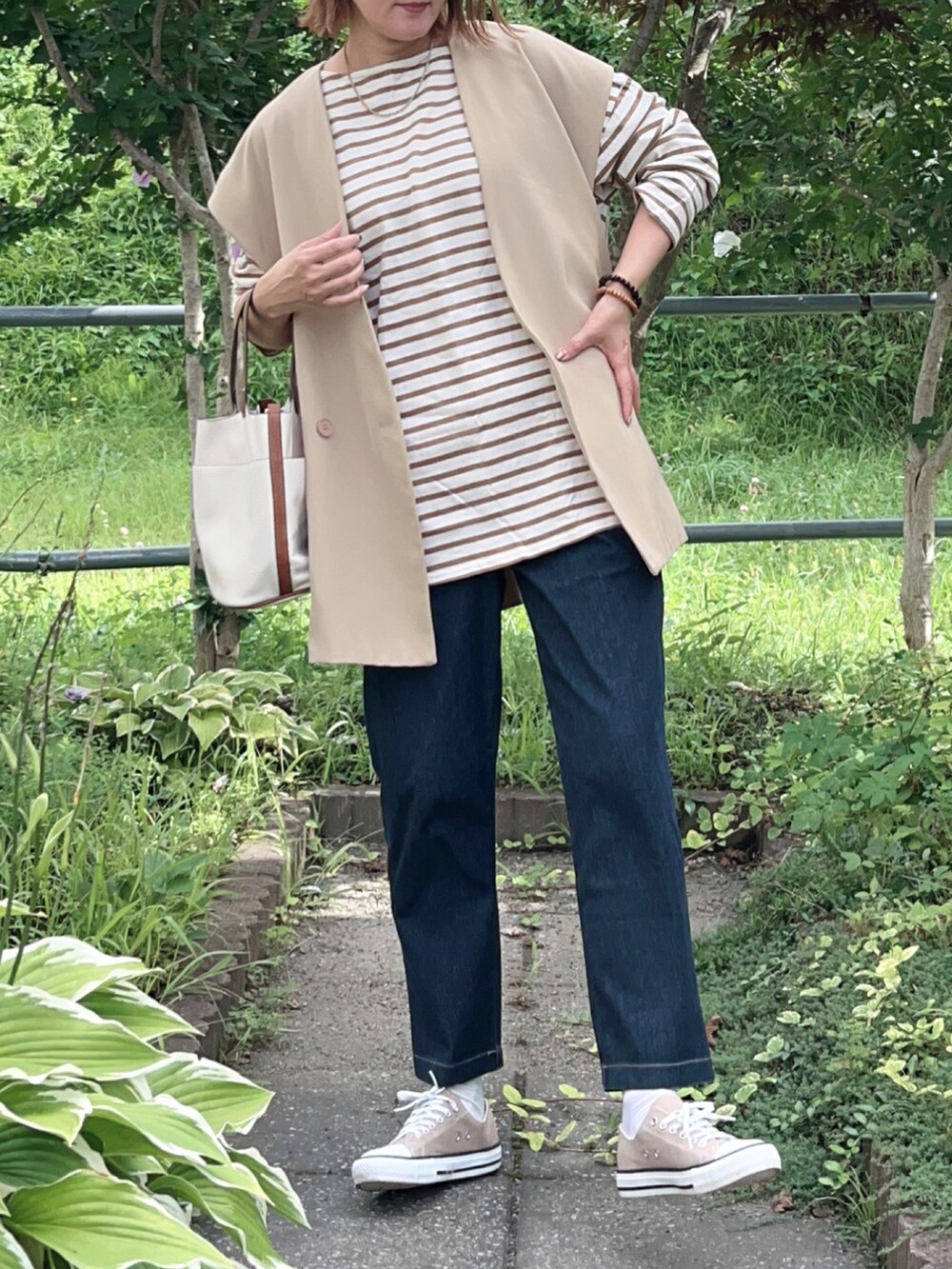ブルー系のその他パンツ、ベージュ系のスニーカー、ベージュ系のベストを着用したレディースの秋コーディネートの5枚目の写真
