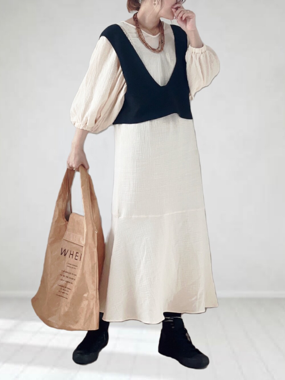 ホワイト系のワンピース、ブラック系のベスト、ベージュ系のトートバッグを着用したレディースの春コーディネートの4枚目の写真