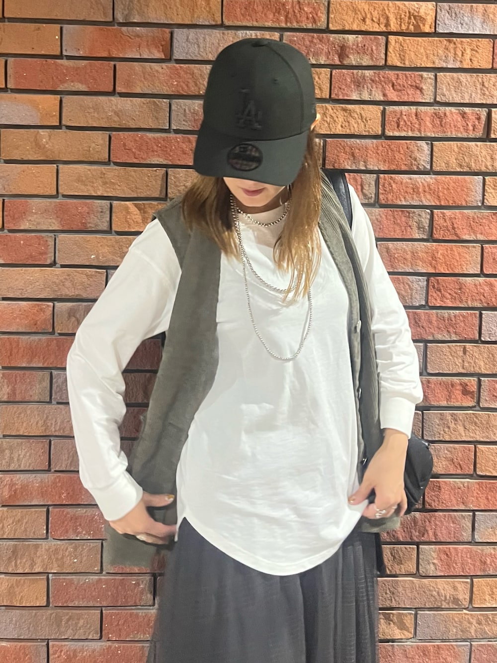 ホワイト系のTシャツ/カットソー、グレー系のスカート、グリーン系のベストを着用したレディースの秋コーディネートの5枚目の写真