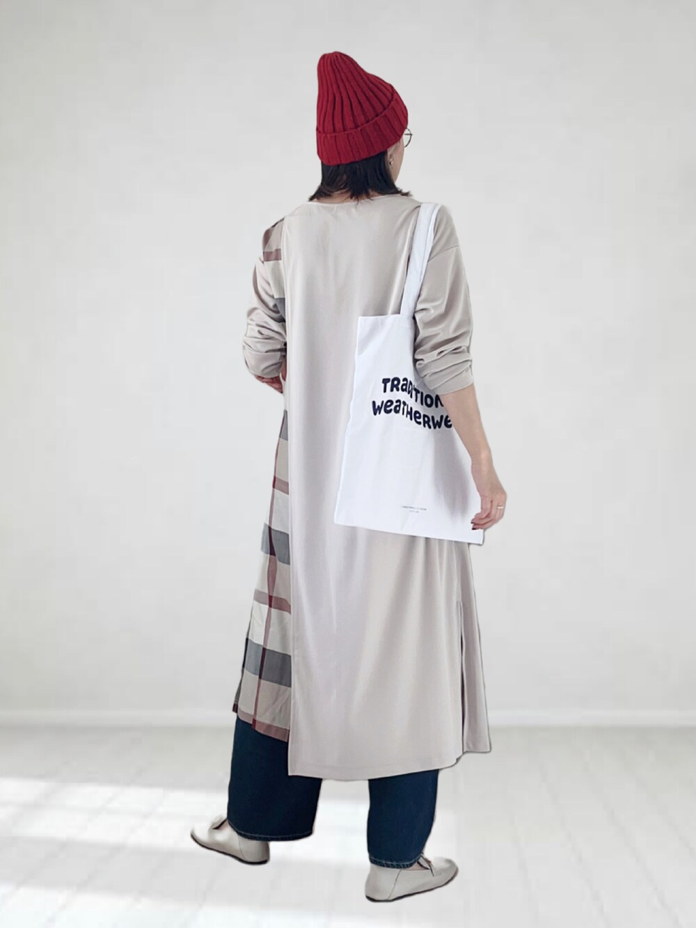 ベージュ系のワンピース、ブルー系のデニムパンツ、ホワイト系のトートバッグを着用したレディースの秋コーディネートの3枚目の写真