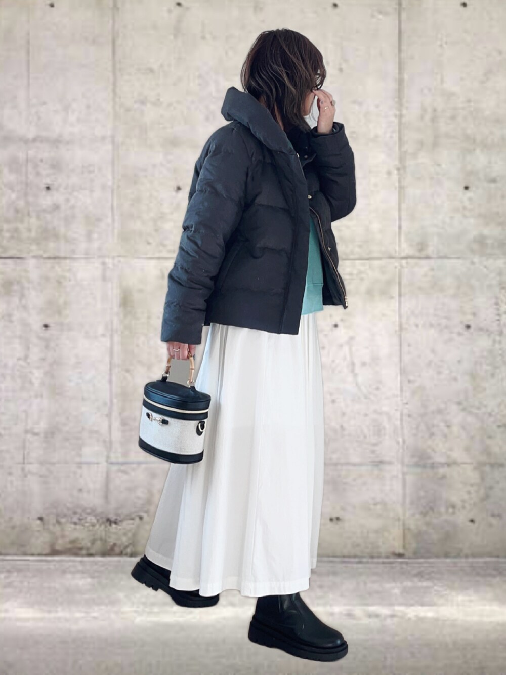 グレー系のダウンジャケット/コート、ブルー系のTシャツ/カットソー、ホワイト系のスカートを着用したレディースの冬コーディネートの2枚目の写真