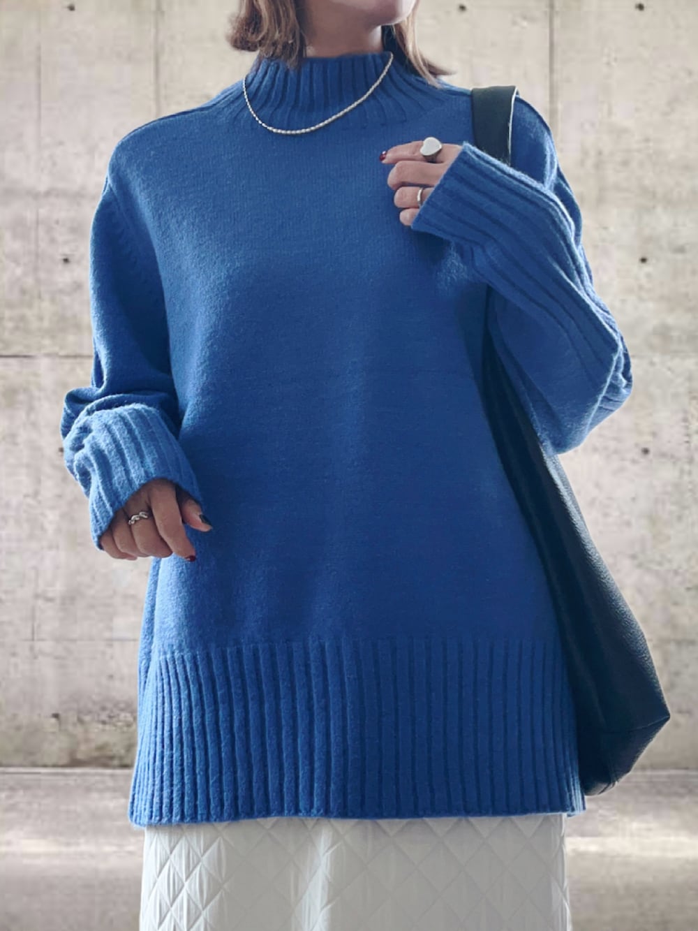 ブルー系のニット/セーター、ホワイト系のスカート、ブラック系のトートバッグを着用したレディースの冬コーディネートの4枚目の写真