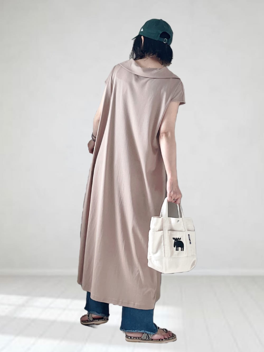 ベージュ系のワンピース、ブルー系のデニムパンツ、ホワイト系のトートバッグを着用したレディースの夏コーディネートの3枚目の写真