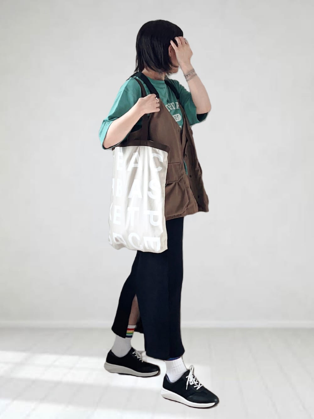 ブラック系のスニーカー、グリーン系のTシャツ/カットソー、ブラウン系のベストを着用したレディースの夏コーディネートの2枚目の写真