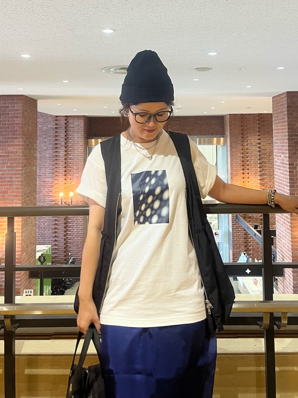 ブラック系のベスト、ブルー系のスカート、ブラック系のサンダルを着用したレディースの夏コーディネートの5枚目の写真