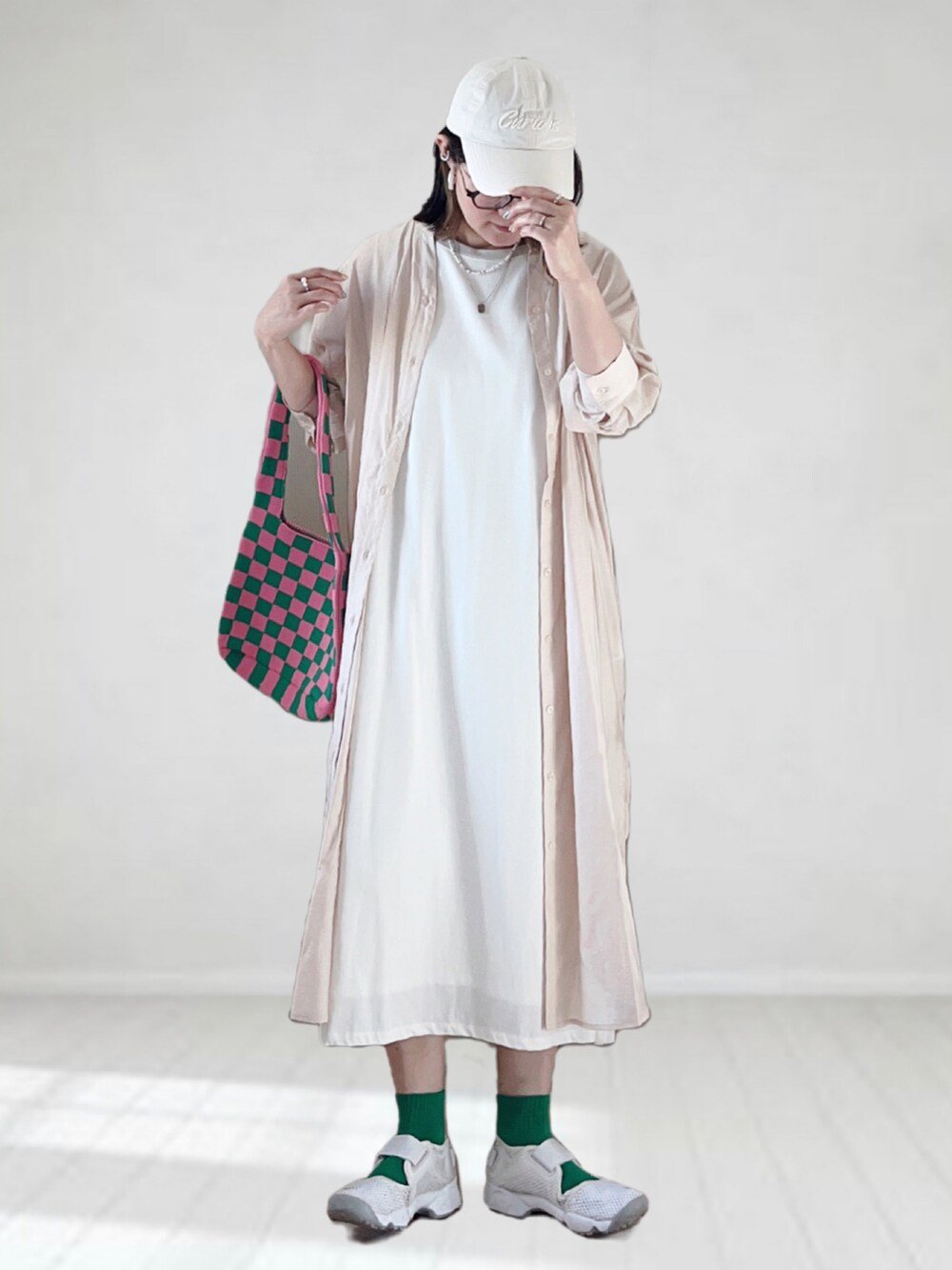 ベージュ系のシャツワンピース、ホワイト系のワンピース、ホワイト系のスニーカーを着用したレディースの夏コーディネートの3枚目の写真