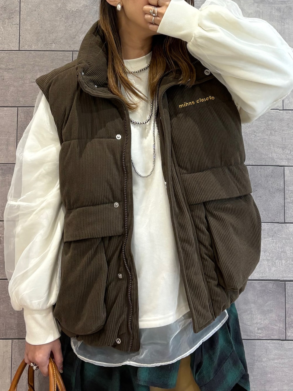 ブラウン系のダウンベスト、ホワイト系のスウェット、グリーン系のシャツ/ブラウスを着用したレディースの冬コーディネートの5枚目の写真