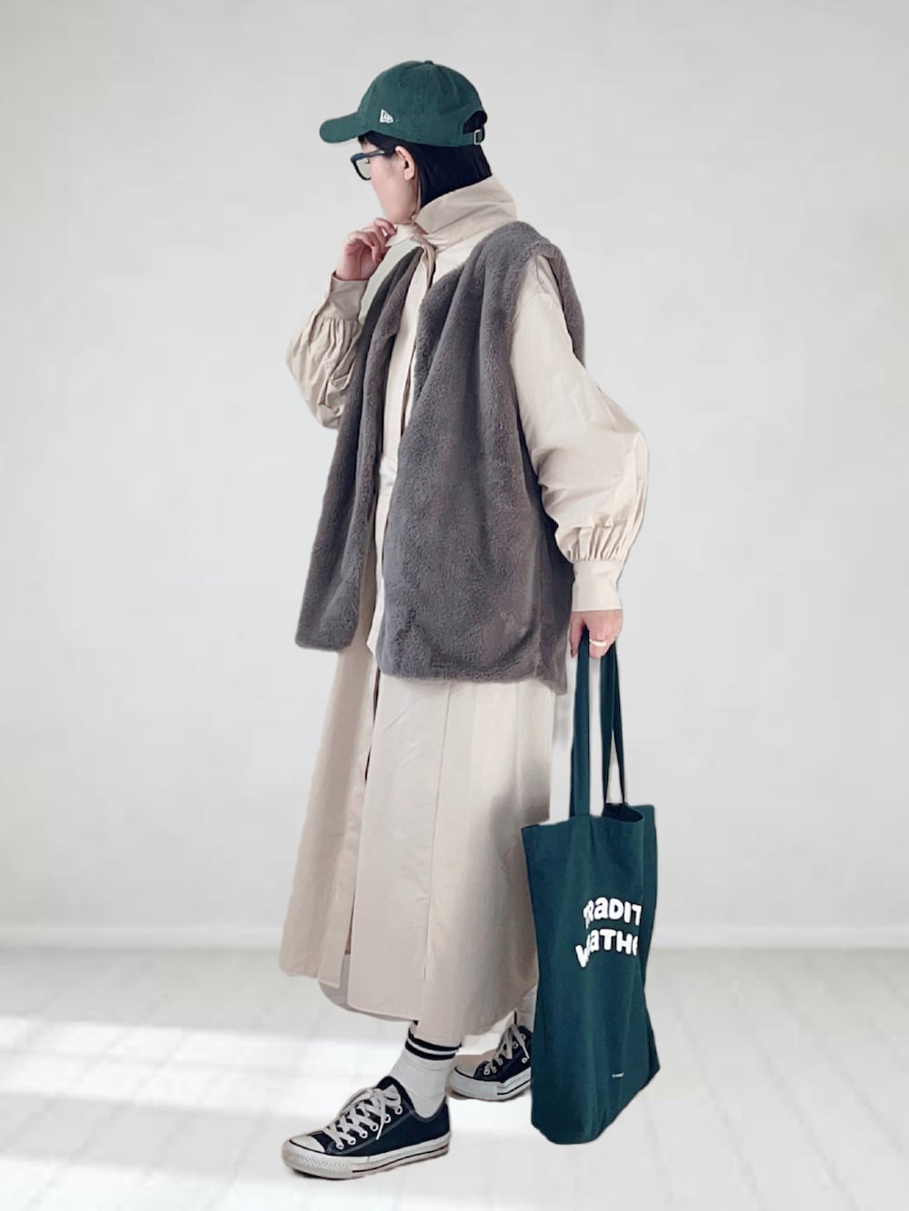 ベージュ系のシャツワンピース、グリーン系のトートバッグ、グレー系のベストを着用したレディースの秋コーディネートの2枚目の写真