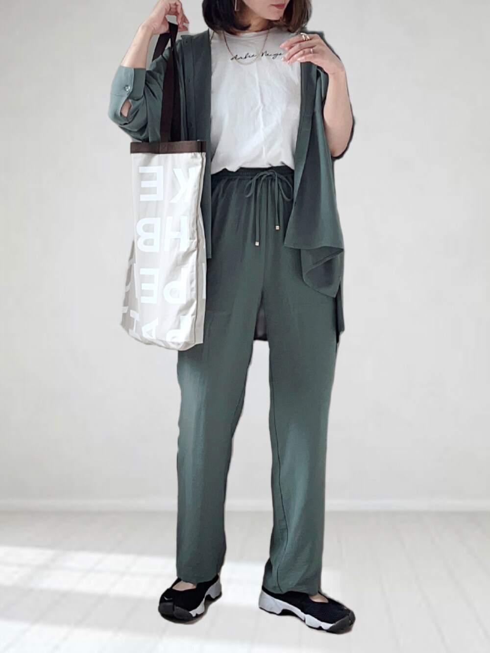 グレー系のトートバッグ、グリーン系のシャツ/ブラウス、ホワイト系のTシャツ/カットソーを着用したレディースの夏コーディネートの4枚目の写真