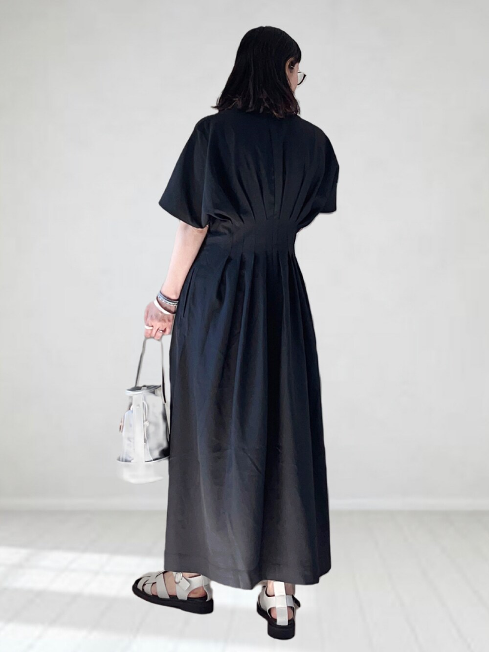 ブラック系のワンピース、シルバー系のショルダーバッグ、ホワイト系のサンダルを着用したレディースの夏コーディネートの2枚目の写真