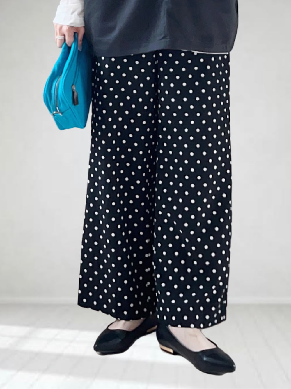 ブルー系のショルダーバッグ、ブラック系のベスト、ホワイト系のTシャツ/カットソーを着用したレディースの春コーディネートの3枚目の写真