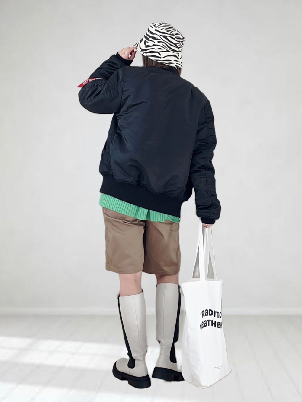 ブラック系のMA-1、ホワイト系のTシャツ/カットソー、グリーン系のカーディガン/ボレロを着用したレディースの冬コーディネートの3枚目の写真