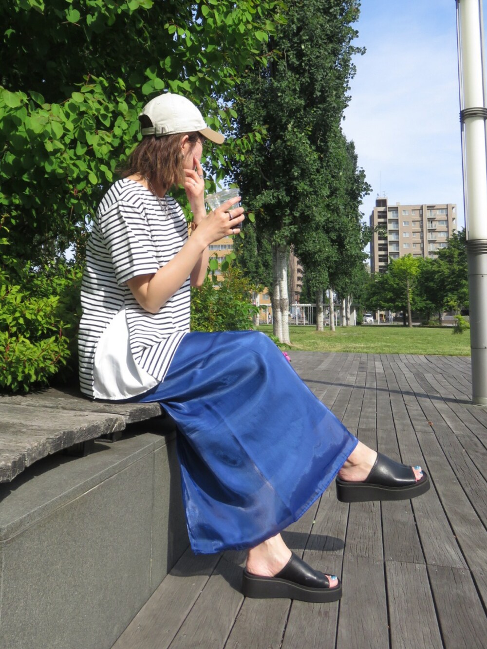 ホワイト系のTシャツ/カットソー、ブルー系のスカート、ブラック系のサンダルを着用したレディースの夏コーディネートの2枚目の写真
