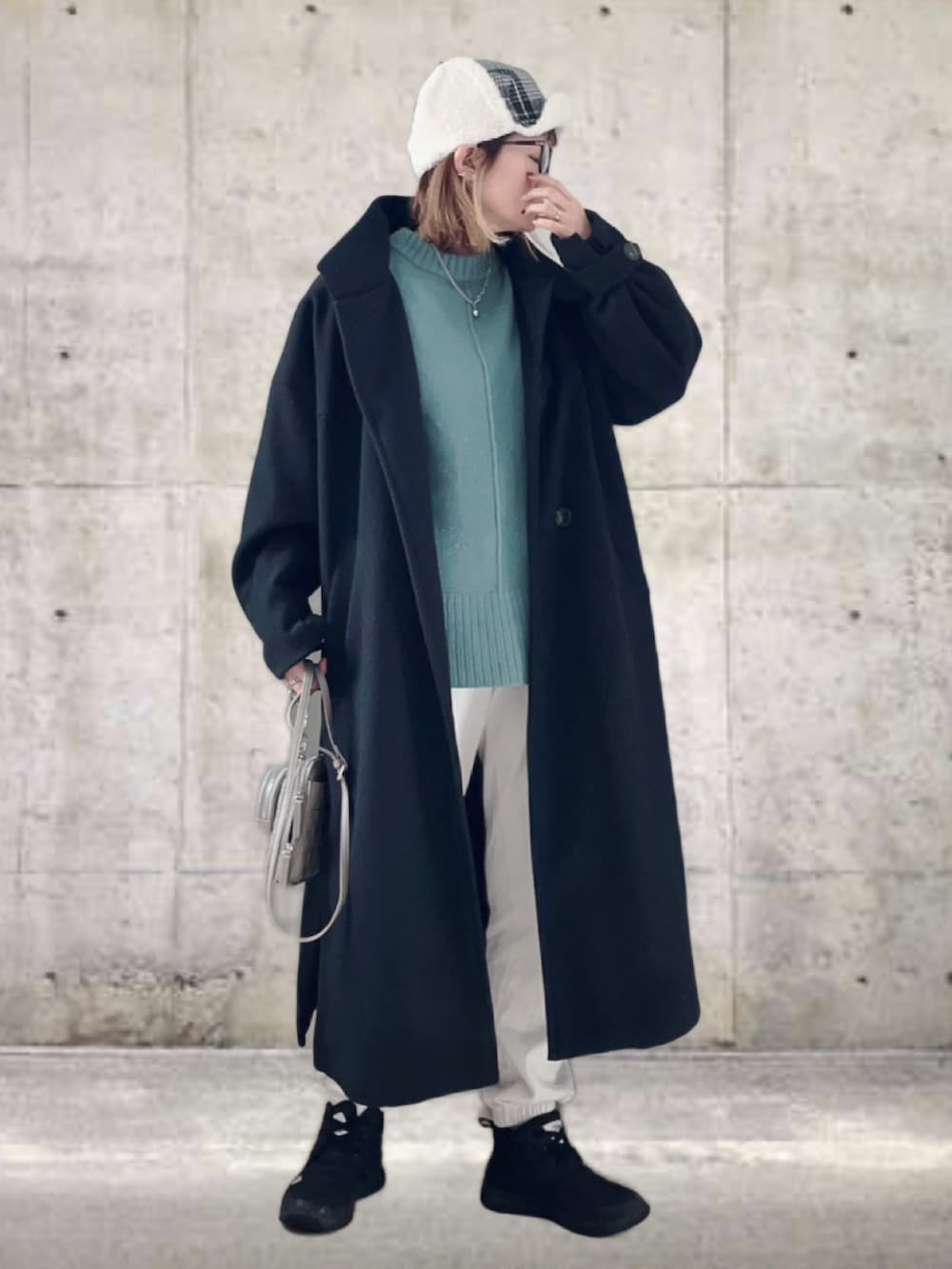 ブラック系のその他アウター、グリーン系のニット/セーター、ホワイト系のスウェットパンツを着用したレディースの冬コーディネートの2枚目の写真