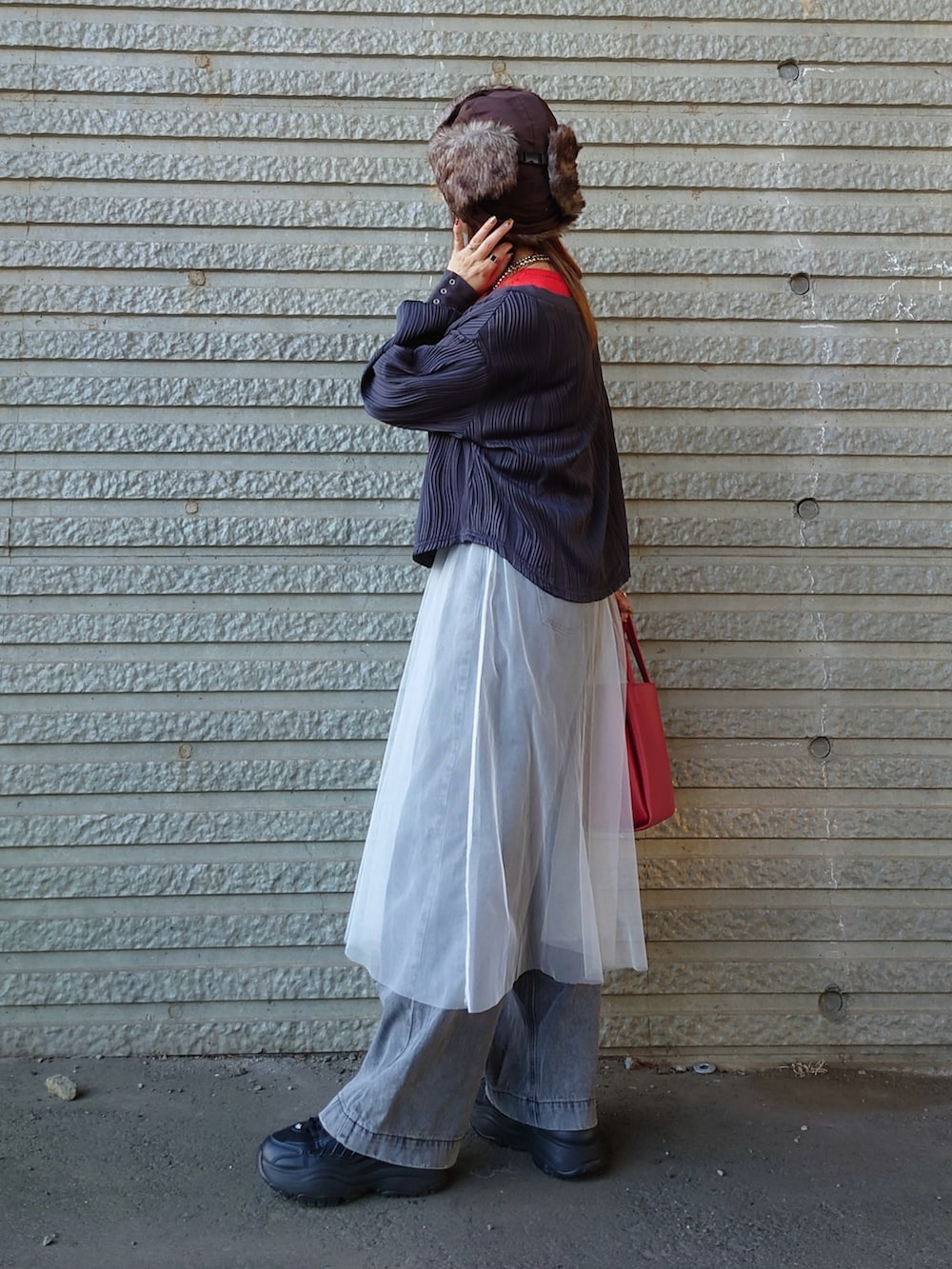 グレー系のデニムパンツ、ブラック系のスニーカー、ホワイト系のスカートを着用したレディースの秋コーディネートの4枚目の写真