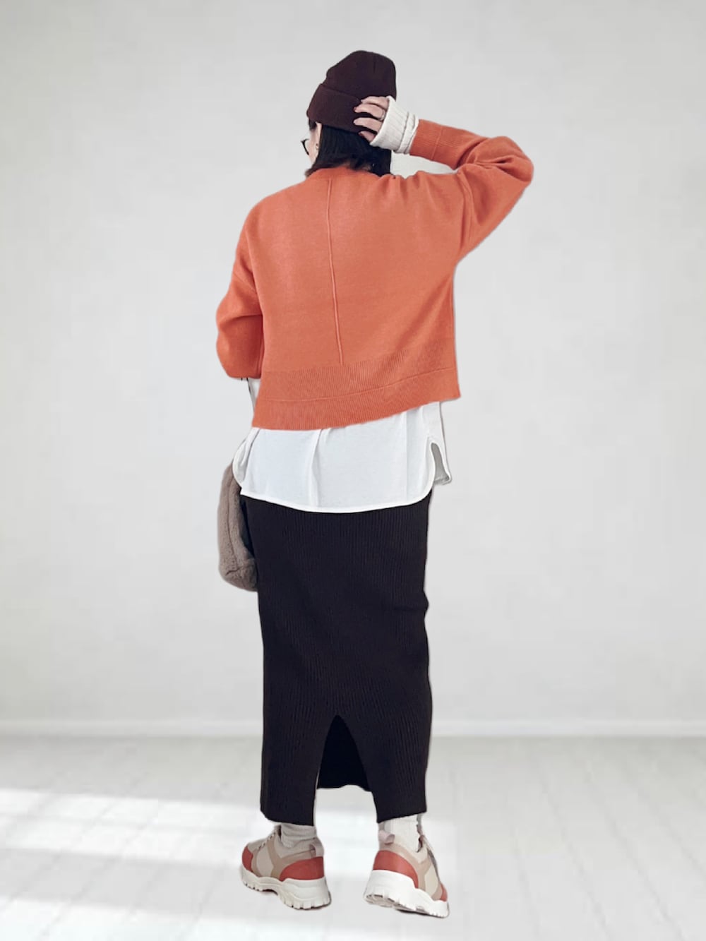 オレンジ系のニット/セーター、ホワイト系のタンクトップ、ブラウン系のスカートを着用したレディースの秋コーディネートの3枚目の写真