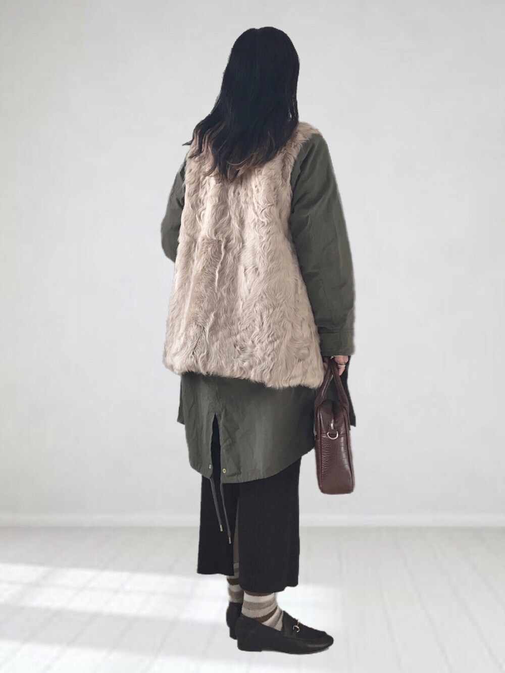 ベージュ系のベスト、グリーン系のモッズコート、ホワイト系のTシャツ/カットソーを着用したレディースの冬コーディネートの2枚目の写真