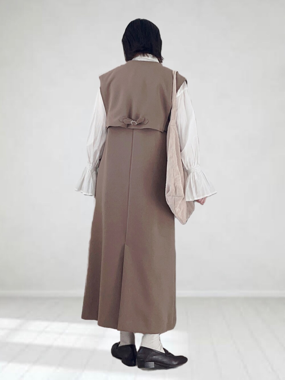 ブラウン系のジャンパースカート、ホワイト系のシャツ/ブラウス、ホワイト系のトートバッグを着用したレディースの秋コーディネートの2枚目の写真