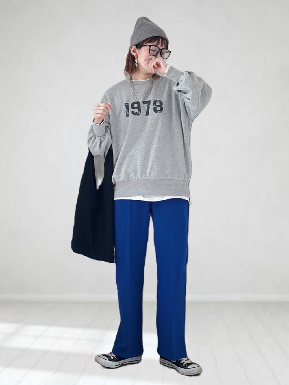 グレー系のスウェット、ブルー系のスラックス、ブラック系のトートバッグを着用したレディースの春コーディネートの2枚目の写真