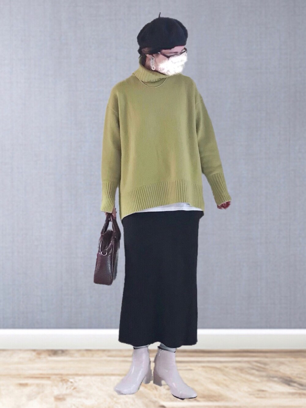 イエロー系のニット/セーター、ブラウン系のスカート、ブラウン系のハンドバッグを着用したレディースの冬コーディネートの2枚目の写真