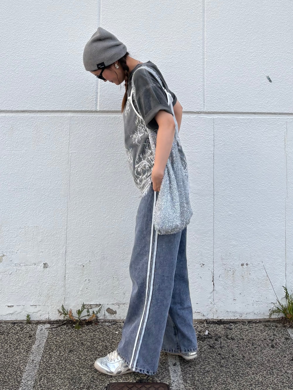 ブルー系のデニムパンツ、シルバー系のトートバッグ、シルバー系のスニーカーを着用したレディースの夏コーディネートの3枚目の写真
