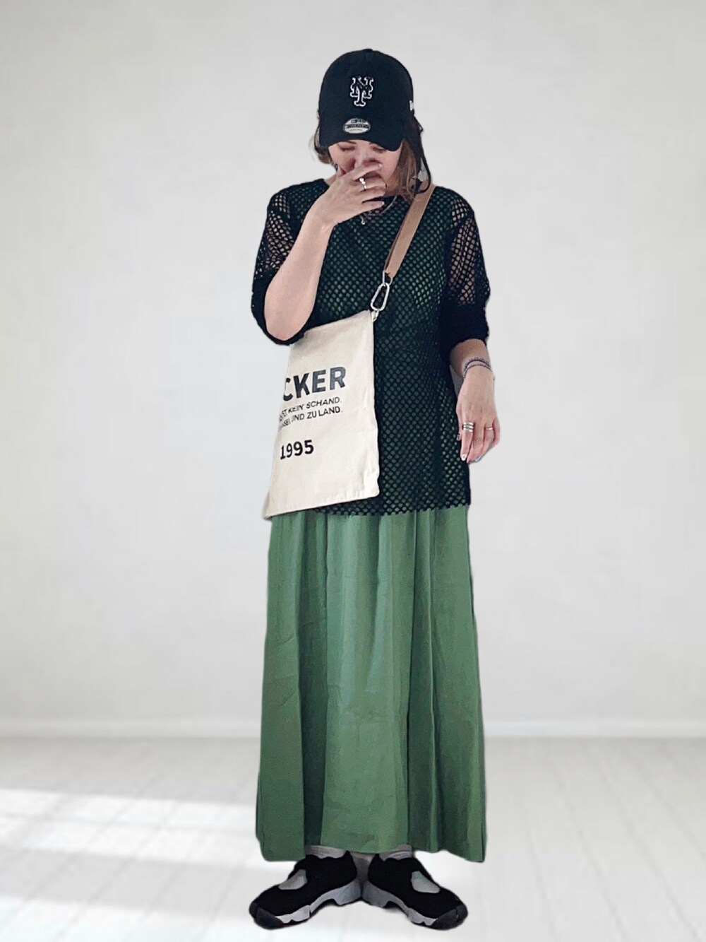 グリーン系のワンピース、ブラック系のTシャツ/カットソー、ベージュ系のトートバッグを着用したレディースの夏コーディネートの3枚目の写真