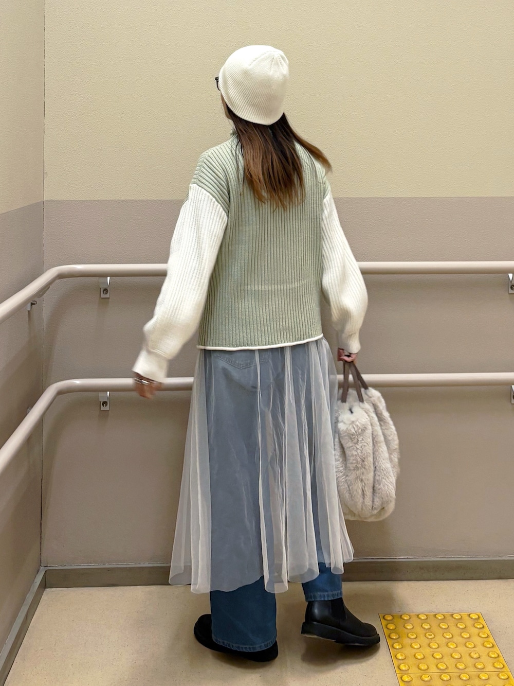 グリーン系のニット/セーター、ホワイト系のスカート、ブルー系のデニムパンツを着用したレディースの冬コーディネートの2枚目の写真