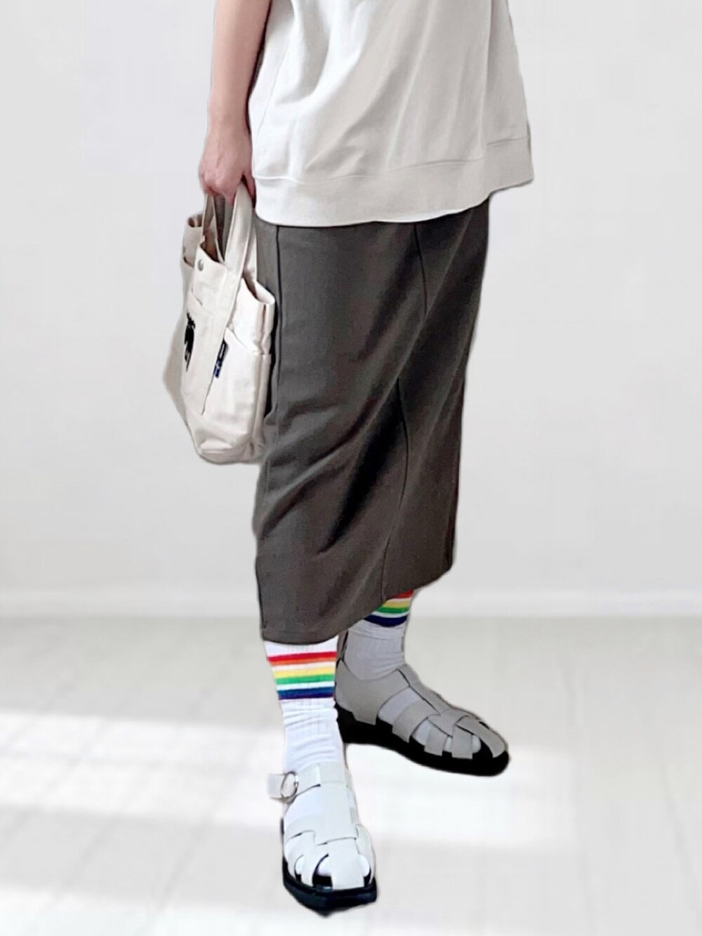 ベージュ系のTシャツ/カットソー、グレー系のスカート、ホワイト系のトートバッグを着用したレディースの春コーディネートの5枚目の写真